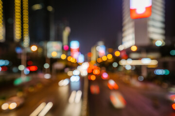City street at night with bright neon lights and blurred car headlights glowing in vibrant colors, creating an energetic urban nightlife scene full of motion.