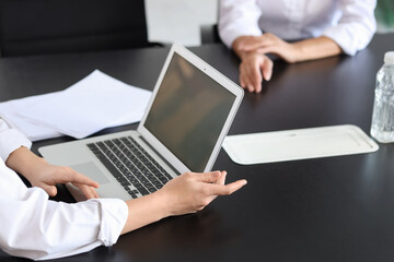 Human resources manager with laptop  interviewing woman at table in office, closeup