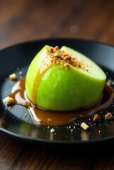 A delectable green apple half, nestled in a rich caramel sauce, adorned with a crunchy crumble topping on a sleek black plate