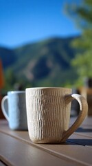 Vibrant photo of two coffee mugs on a wooden table with a mountain view in the background