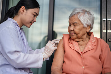 doctor holding syringe and making injection vaccine to senior woman