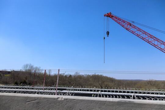 Large red crane stands tall at construction site under concrete bridge reconstruction