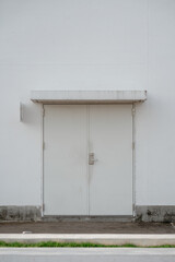 Closed white double metal service doors on a modern industrial or commercial building exterior facade.
