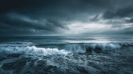 Fototapeta premium Ocean waves break forcefully on the sandy beach as dark clouds gather overhead. The scene captures the intensity of a storm approaching at dusk.