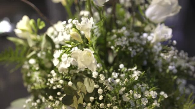 Slow push-in close-up on white freesia and gypsophila bouquet with soft lighting