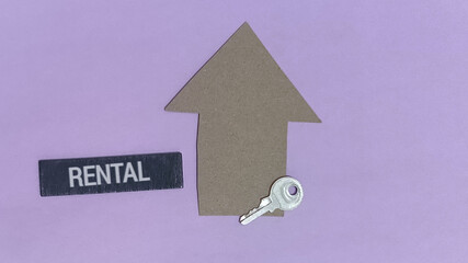 Rental property concept featuring a cardboard house, key, and the word 'RENTAL' against a purple backdrop