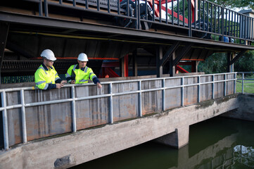 Naklejka premium A professional engineer and an inspector are jointly seriously inspecting the water filtration of a water filter inside a treatment pond.