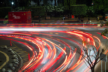 Long-exposure shot capturing dynamic red and white light trails from fast-moving vehicles on a...