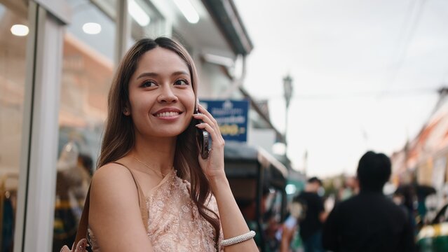Thai woman talking on smartphone in traditional dress on lively street
