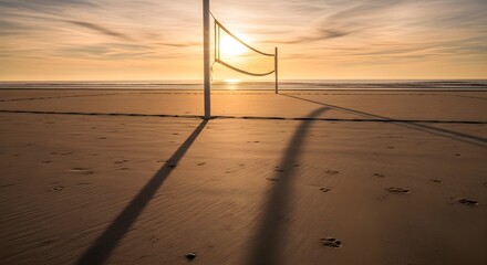 Beach volleyball net at sunset with long shadows stretching across the sand
