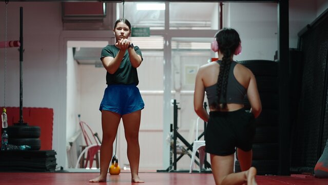 Young women training muay thai technique in gym, focused on martial arts practice