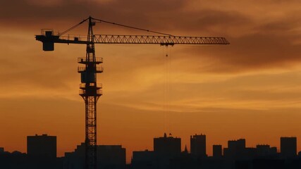 promotion Industrial tower crane construction silhouetted by the setting sun during urban development and building construction with copy space