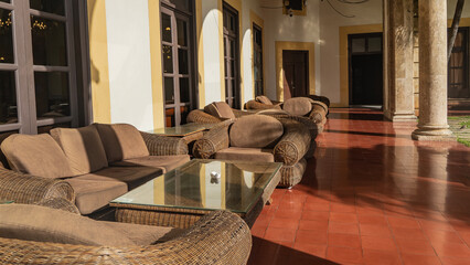 A place to relax on the terrace. Wicker rattan sofas, armchairs with soft cushions on the seats. Tables with glass tops. Tiled floor. Cuba. Havana