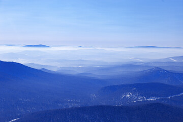 Aerial view of mountain ridges in soft fog. Beautiful white blue Peaks fades into distance. Minimal Nature abstract landscape, natural gradient color, environment winter serenity, panoramic skyline.