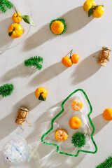 Winter holiday flat lay pattern, festive table setting concept, citrus fruits, champagne corks, plate Christmas tree form with soft shadows, beautiful sunlight reflections. New Year party background.