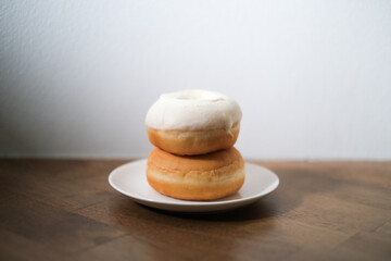 Breakfast donut in white plate on wooden table.