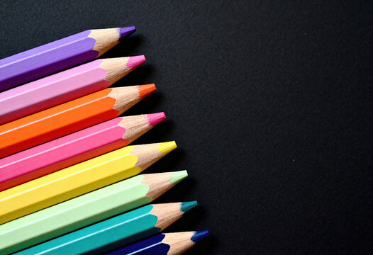 Row of colorful pencils arranged diagonally on dark background creating vibrant contrast for creative art projects