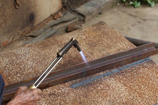Metalworker using a torch to cut through a piece of steel