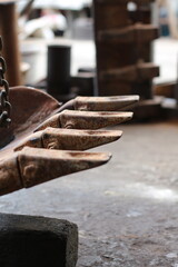 Close-up of a rusty excavator bucket teeth in a workshop setting