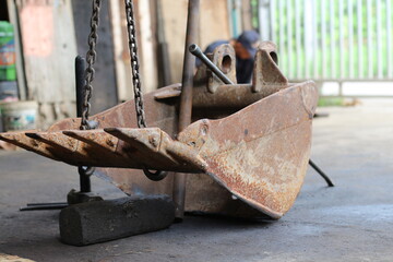 Close-up of a rusty excavator bucket in a workshop setting