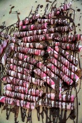 Fototapeta premium Chocolate covered pretzels with pink and white icing on a table