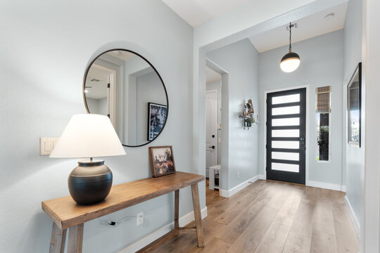 A hallway featuring a table, a lamp, a mirror, and a door