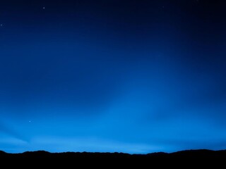 Dark to light blue night sky gradient, silhouetted mountains below, starry backdrop,  dark blue,  sky