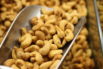 Raw cashew nuts with metal scoop showing whole kaju natural cream colored texture closeup