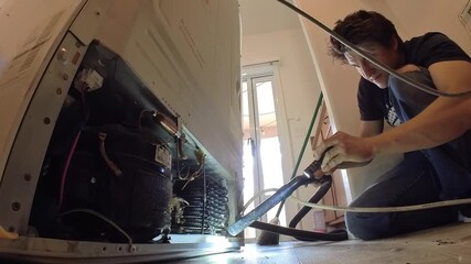 A technician expertly repairs a refrigerator, showcasing his skills