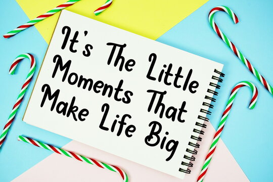 It's The Little Moments That Make Life Big message of season holidays written on notepad with candy cane decoration on pastel background