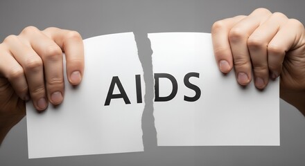 Hands tearing paper with the word “AIDS”, symbolic fight against HIV