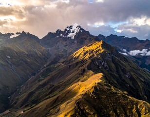 Aerial view of a mountain range with snowy peaks, under a cloudy sky