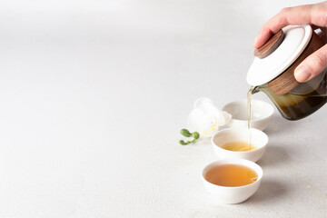 Warm herbal tea poured into delicate white cups on a rustic wooden tray, minimal composition with orchid detail, symbolizing calmness, relaxation, and mindful living.