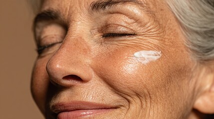 A serene elder woman smiling with a moisturizing cream on her cheek, embodying beauty and self-care in daily life.