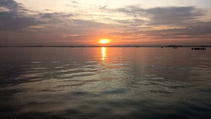 A calm sunset over the ocean, reflecting warm orange light on the gentle waves