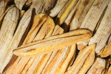 commercially prepared sun-dried bananas (Kluay Tak), a popular sweet snack or dessert ingredient in Southeast Asia. The bananas are peeled, sliced/flattened, and dehydrated, showing an appealing golde