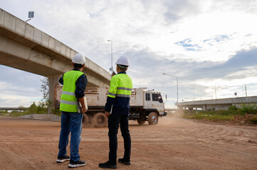 Construction engineers supervise dump truck operation at road construction site. Inspect new road construction, civil engineer working outdoors, infrastructure development in Thailand Asia.