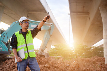 An engineer supervising road construction at infrastructure site with walkie talkie. Inspect structure, supervise new road construction, civil engineer working outdoors.