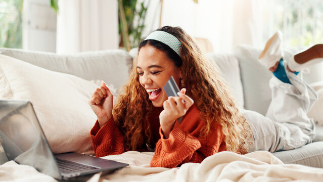 Credit card, laptop and celebration with woman on couch for online shopping, ecommerce and sale. Payment, banking website and person excited in lounge of home for deal, transaction or subscription