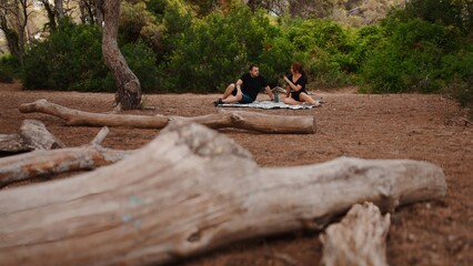 Couple relaxing on blanket in forest, enjoying nature and outdoor leisure time