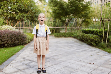 Naklejka premium Schoolgirl back to school after summer vacations. Pupil in uniform smiling early morning outdoor.