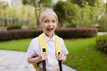Schoolgirl back to school after summer vacations. Pupil in uniform smiling early morning outdoor.