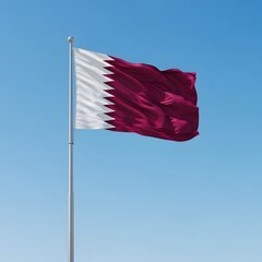The national flag of qatar waving proudly against a clear blue sky on a sunny day