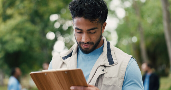 Clipboard, volunteer and writing with man in park for donation, community service and ngo project. Nonprofit checklist, grocery distribution and food drive with person outdoor for outreach program - Powered by Adobe