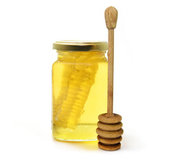Liquid natural honey in glass jar with wooden dipper and honey combs isolated on white