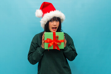 Surprised woman in Santa hat reacts while holding a gift box Ideal for Christmas surprise themed campaigns and visuals