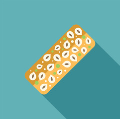 Rectangular nougat candy bar sprinkled with pistachios and hazelnuts lying on a blue background with a long shadow