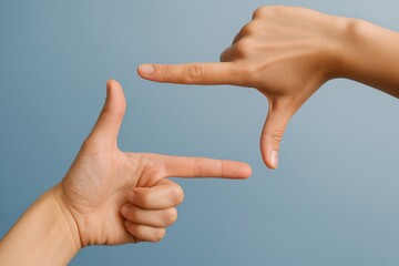 Creative hand gestures forming a frame against a soft blue background. Concept of photography, perspective, and visual storytelling in art and design.
