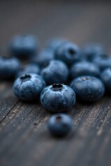 A cluster of bitten berries, as if a wild creature had a recent feast. A small pile of fresh blueberries, with a few showing tiny, precise bite marks. Scattered on a rustic, dark wooden surface. Soft