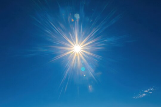 Bright sun shines radiantly against clear deep blue sky, creating a warm and uplifting atmosphere at midday